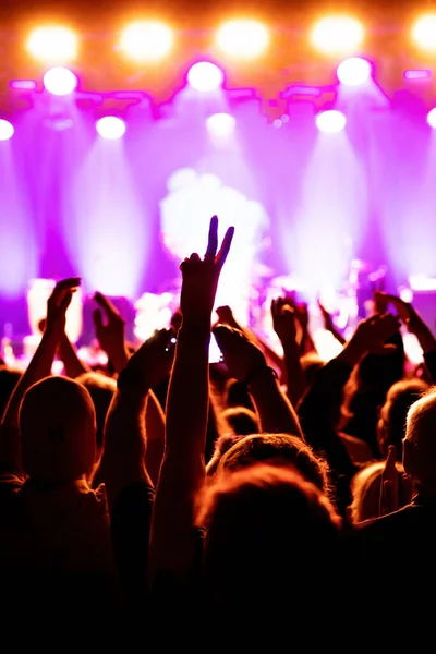 Concert hall with a lit stage and people silhouettes during a concert