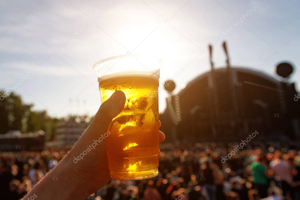 Disposable beer glass in mans hand at a summer music festival