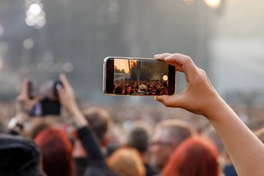 Smartphone in the hand of a music fan at the summer concert