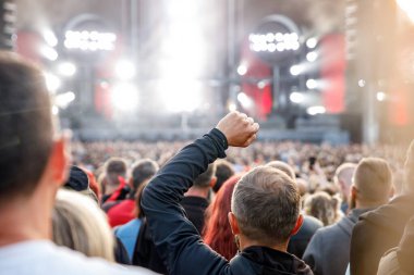 Crowd, happy people enjoying a rock concert, raised up hands and clapping with pleasure