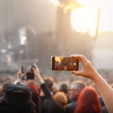 People holding their smartphones at concert and taking pictures
