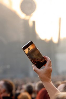 People holding their smartphones at concert and taking pictures