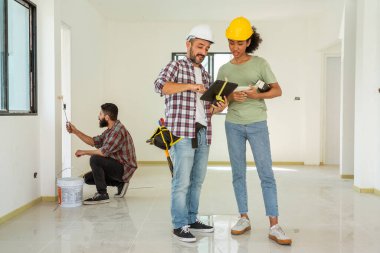 Elektrik müteahhiti elektrik dolaplarını incelemek ve onarmak için merdivenleri çıkmış. Foreman ekibi de inşaatı bir kadın işçinin inşaatta durduğu kadar doğru şekilde incelemiş..