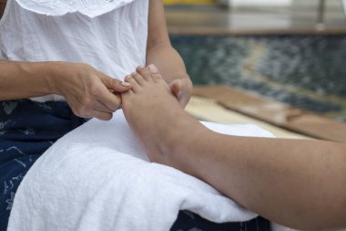 Ayak spa 'sı ve güzellik konsepti. Masöz bacaklarını ve ayaklarını temizler, kucağına koyar, kurutmak için kuru bir havlu kullanır. Sonra da tatil köyü ve kaplıca salonunun yanındaki havuza masaj yapar..