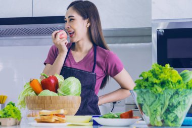 Mutfakta salata sebzeleri ve organik meyvelerle duran Asyalı kadın sağlıklı besleniyor.