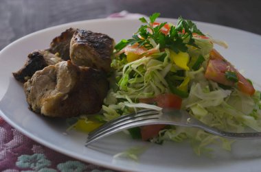 Taze salata, barbekü, patates cipsi, marul ve taze ev yapımı salatalık şişleri. Porsiyon beyaz tabakta