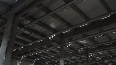 Endüstriyel bir tekstil şirketinin büyük bir deposunun metal tavanı. Büyük deponun tavanında floresan lambaları var.