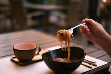 Terasta bir restoranda pirinç eriştesi yiyen adam. Tabakta ramen, Tayland yemeği.