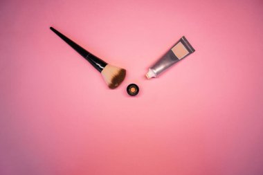 Pembe arka plan manzaralı fırçalı yüz için temel. Makyaj malzemeleri. Yüz için dekoratif komedi. yüz bakımı ürünü