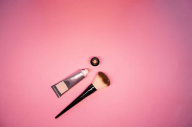 Pembe arka plan manzaralı fırçalı yüz için temel. Makyaj malzemeleri. Yüz için dekoratif komedi. yüz bakımı ürünü