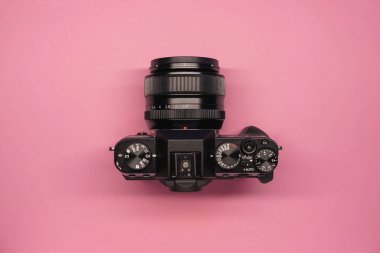 Pembe arka plan manzaralı modern aynasız kamera. Fotoğrafçılıktaki modern teknolojiler. blog yazarının aksesuarları
