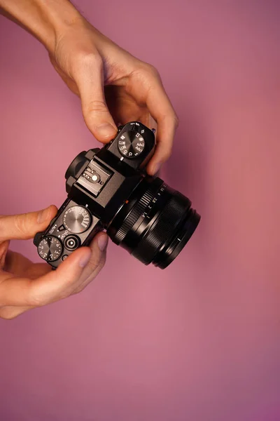 一个男人拿着一个没有镜子的相机在粉红色的背景图片上方 摄影师用相机拍照 现代照相机 — 图库照片