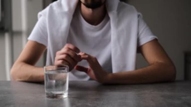 Aspirinin bir bardak suda çözülmesini bekleyen baş ağrısı olan bir adamın portresi.