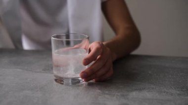 Aspirinin bir bardak suda çözülmesini bekleyen baş ağrısı olan bir adamın portresi.