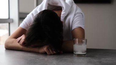 Aspirinin bir bardak suda çözülmesini bekleyen baş ağrısı olan bir adamın portresi.