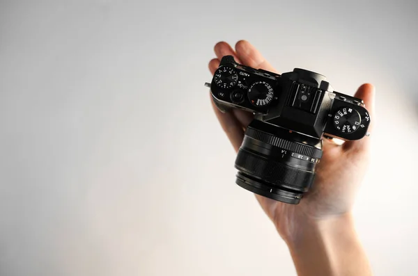 一个男人手里拿着一架紧凑型现代Slr相机 在白色的背景图片上方 — 图库照片