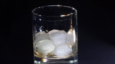 Rom, arka planda buzlu bir bardağa doldurulur. Alkollü bir bardağın yakın plan görüntüsü.