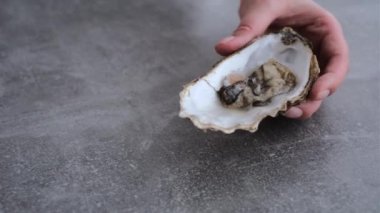 Taze istiridye tutan ve limon suyu döken eller.