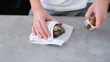 Profesyonel şef bir istiridyeyi havlunun ucunda bıçakla açar.