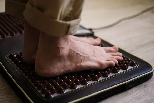 a man stands on a foot massager with spikes close-up of the foot
