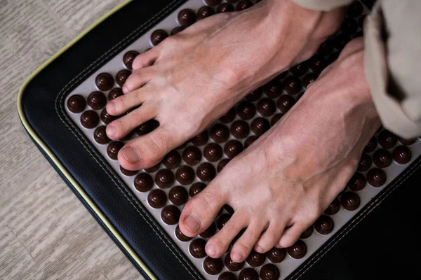 a man stands on a foot massager with spikes close-up of the foot