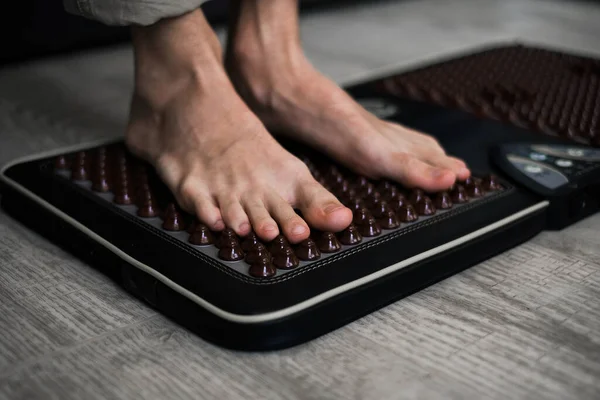 a man stands on a foot massager with spikes close-up of the foot