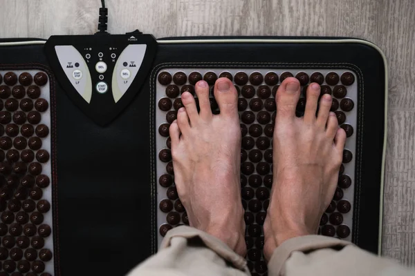 a man stands on a foot massager with spikes close-up of the foot