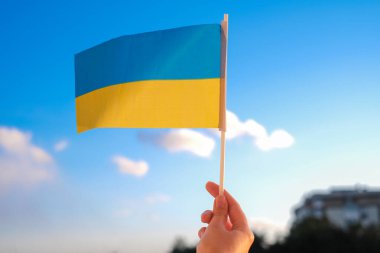 Ukrayna bayrağını mavi gökyüzüne karşı tutan kadın eli