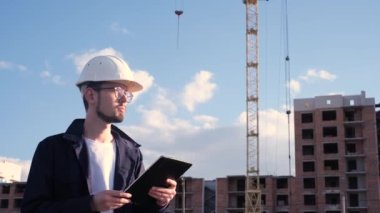 İnşaat alanında elinde tabletle mühendis müfettişi inşaatın nasıl gittiğini kontrol etti.