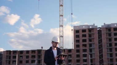 İnşaat alanında elinde tabletle mühendis müfettişi inşaatın nasıl gittiğini kontrol etti.