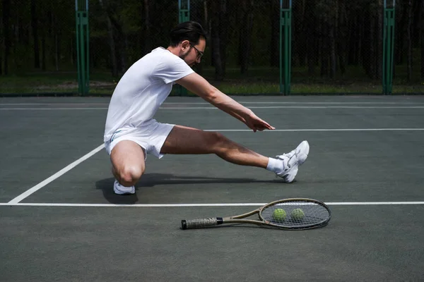 Genç adam tenis oynamadan önce spor sahasında ısınıyor.