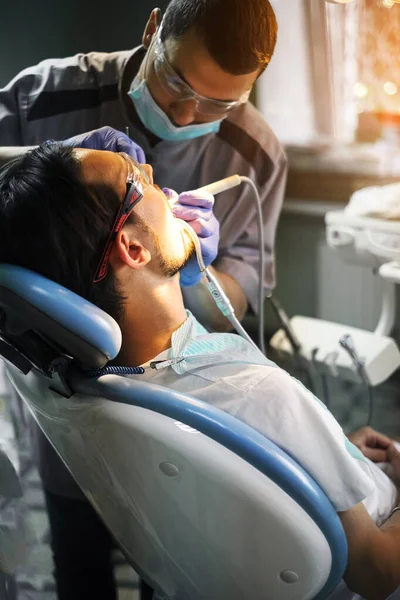 a young man sits in a dentist\'s chair and treats his teeth