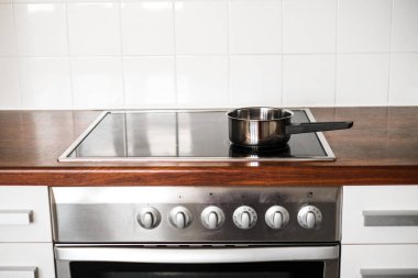 Mutfaktaki ocağın üzerinde metal bir tencere duruyor. Mutfak aksesuarı