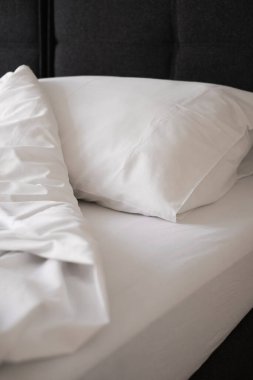 Yatak manzarasında beyaz yastık ve battaniye. Bir otel odasında yatak.