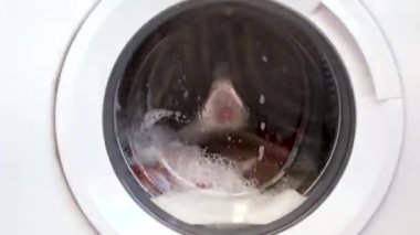 Çamaşır makinesi eşyaları yıkıyor. Yakın çekim davul.