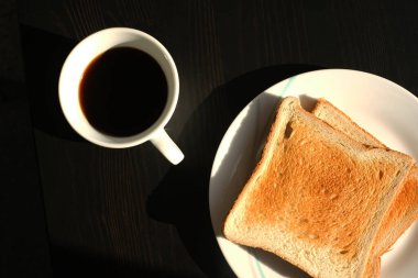 Kahvaltınızda kızarmış ekmek ve siyah masa manzaralı kahve.