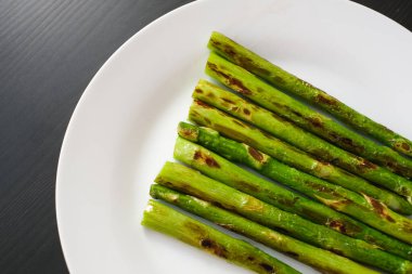 Masanın üst tarafında beyaz bir tabakta kızarmış kuşkonmaz.