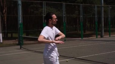 Erkek sporcu tenis oynamadan önce sahada egzersiz yapıyor.