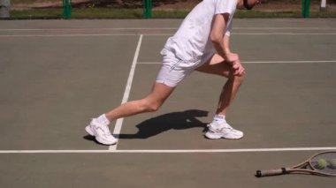 Erkek sporcu tenis oynamadan önce sahada egzersiz yapıyor.