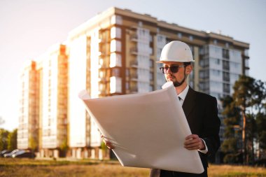 Bir inşaat mühendisi inşa edilmiş evi inceler ve teknik planla karşılaştırır.