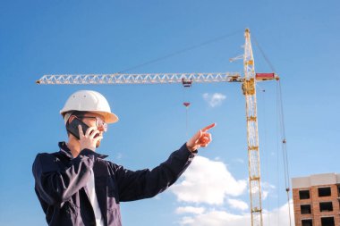 portrait of an engineer in a protective helmet at a construction site talking on the phone