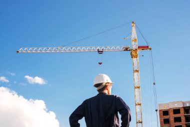 engineer in uniform and safety helmet at construction site checks work