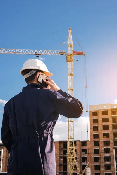 portrait of an engineer in a protective helmet at a construction site talking on the phone
