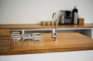 Ahşap mutfak atölyesi, temiz cam bardaklar ve musluk.