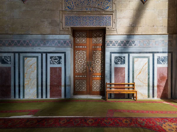 装飾的な木製のドア、モザイク装飾された壁、木製のベンチ、そして床は、日光に照らされています、アル・リファイモスク、カイロ、エジプト — ストック写真