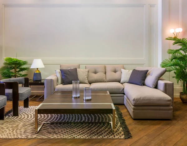 Sofá cinza com almofadas coloridas colocadas e mesa no tapete em espaçoso quarto moderno com poltronas e plantas envasadas verdes — Fotografia de Stock