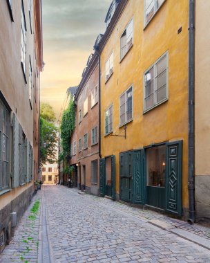 İsveç 'in eski Stockholm kasabası Gamla Stan' de eski tarz turuncu renkli evleri ve Stockholm, İsveç 'teki kaldırım taşı sokağıyla dar bir sokak.