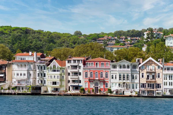 İstanbul Boğazı 'nın Asyalı tarafındaki yeşil dağların denizinden bir yaz günü geleneksel evler ve sık ağaçlarla manzarayı izleyin.