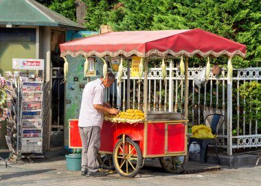 İstanbul, Türkiye - 30 Ağustos 2022: Sultanahmet Meydanı 'nda geleneksel Türk fast food arabasında mısır satan orta yaşlı adam