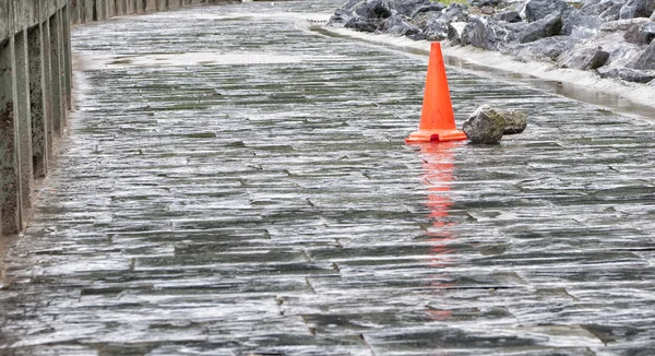 Cône rouge sur une route mouillée — Photo